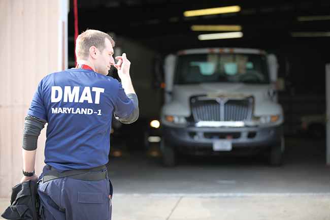 DMAT personnel directs truck pulling out of a garage.