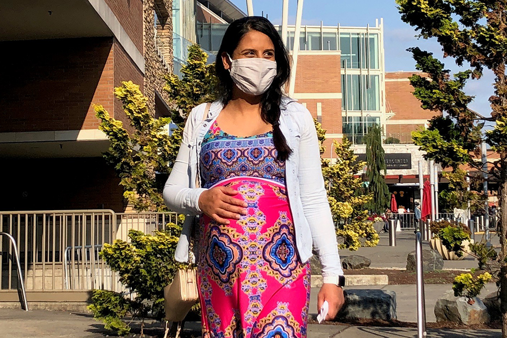 Pregnant woman walking in the city wearing a cloth protective mask