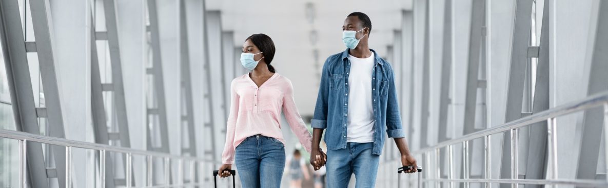 couple wearing protective masks walking through airport