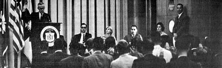 FDA Commissioner Goddard standing behind a podium, with a group of men and women seated in front of him