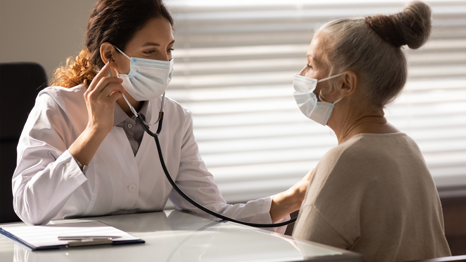 Doctor in office checking a woman's heart beat.