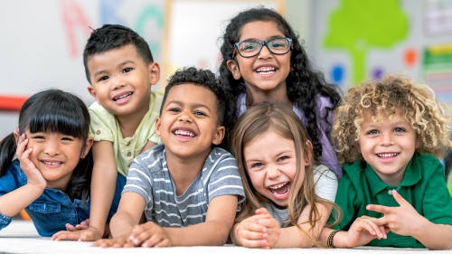 Photo of diverse group of small children smiling in a classroom