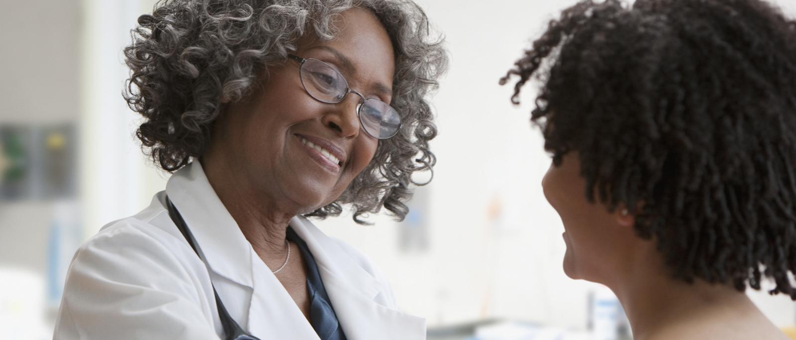 Doctor talking to patient with hand on patient's shoulder.