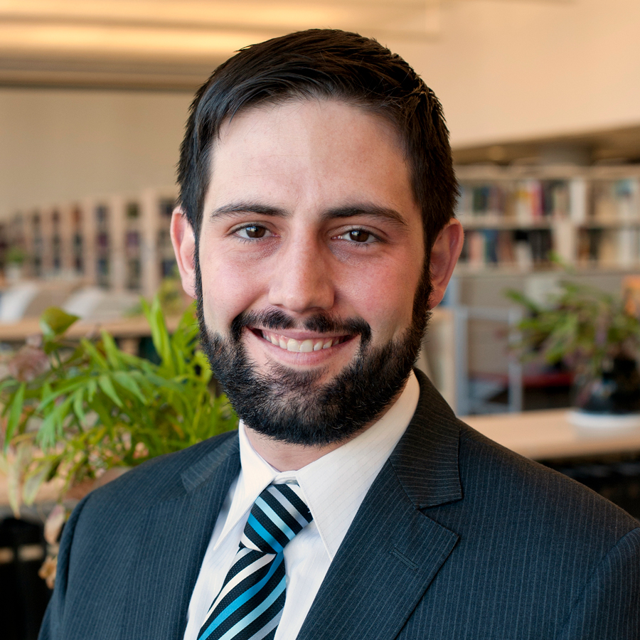 Portrait of David Strauss, M.D., Ph.D, shown from the shoulders up, in the FDA library, wearing a suit, looking at the camera and smiling