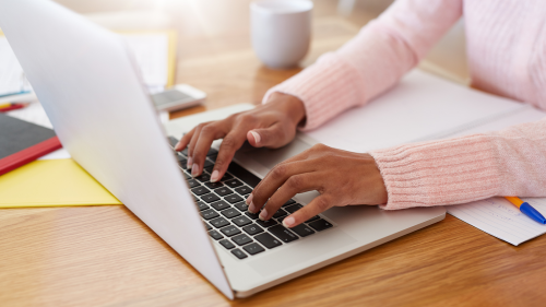 young African-American woman's hands typing on laptop keyboard