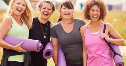 Portrait Of Mature Female Friends On Outdoor Yoga Retreat Walking Along Path Through Campsite