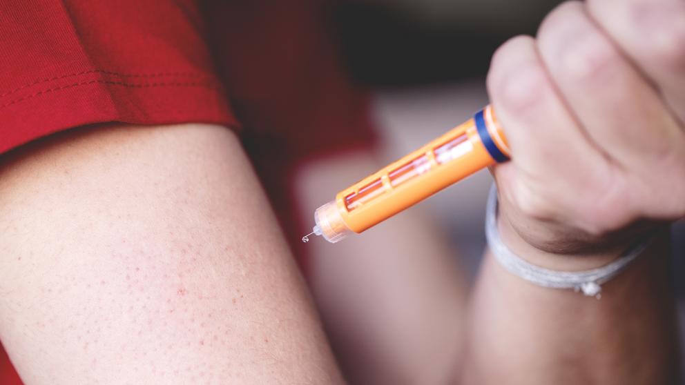 A person prepares to use a generic auto-injector to give themself a drug dose