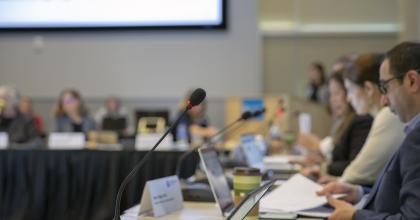 A microphone juxtaposed against blurred panel members of an advisory committee in the background