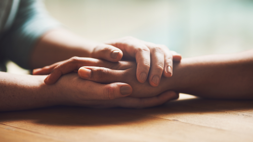 Close-up photo person holding the hand of another person, showing of support.