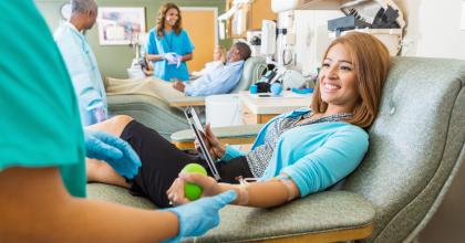 Smiling young asian woman donating blood in clinic.