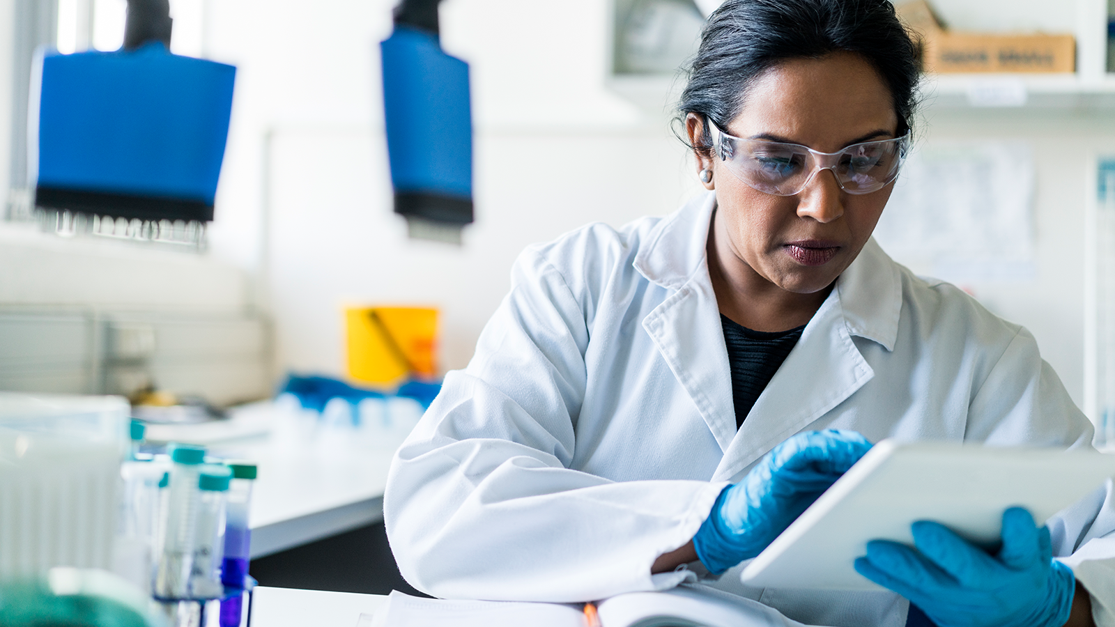 A female scientist wearing PPE and using a white tablet