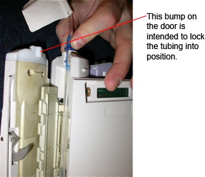 Photo of tubing set properly aligned in its channel, showing how the bump on the door locks the tube in place.