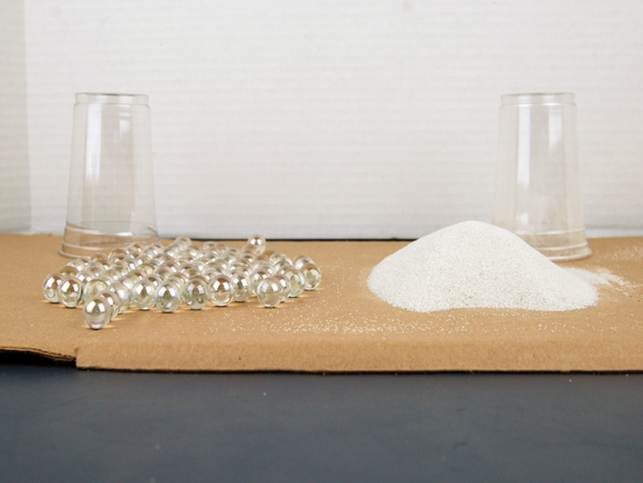 Cup of marbles and sand dumped on table