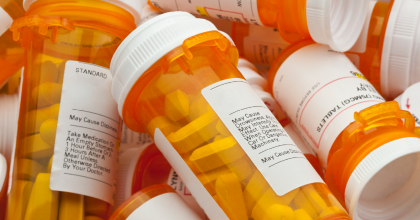 Close up image of a pile of prescription pill bottles with pills in them