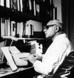 Walter Modell seated at a desk, typing on a typewriter