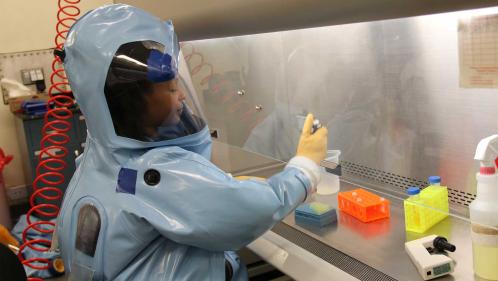 A participant in a data quality course conducts a training exercise wearing BSL-4 personal protective equipment.