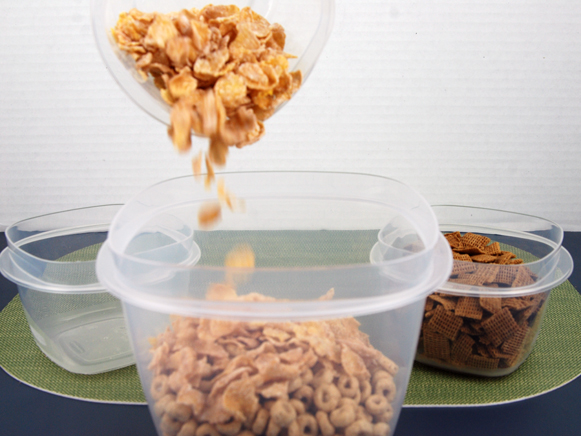 Cereal being poured from small bowl to bigger bowl