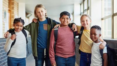 Group of kids smiling and draping their arms around one another.