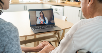 Seated Woman and Man in Wheelchair looking at an image on a laptop screen of a Female with a stethoscope.