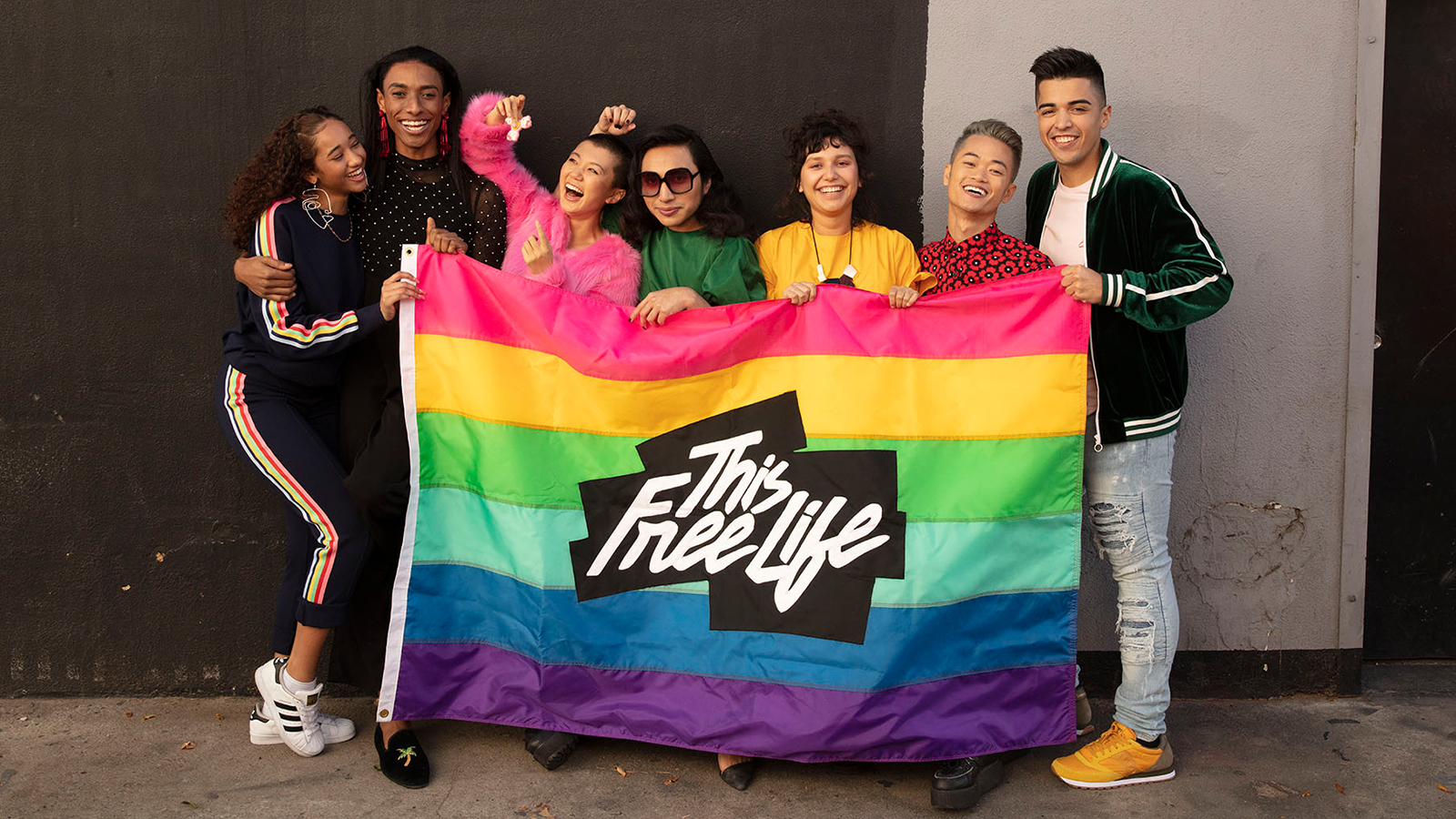 youth standing in front of a This Free Life rainbow flag