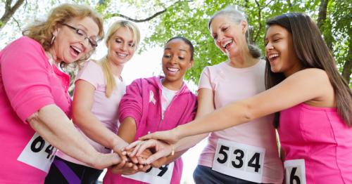 group of women wearing pink shirts holding hands together