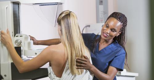 Woman being positioned for a mammogram by a healthcare technician 