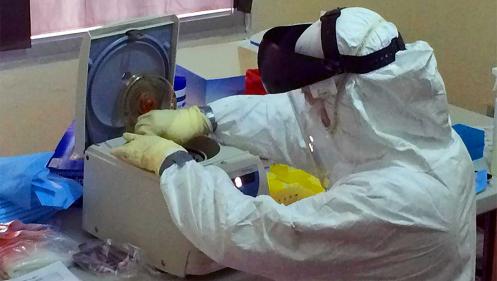 U.S. Navy Lt. Andrea McCoy tests a patient sample for the Ebola virus at a Naval Medical Research Center mobile laboratory in Liberia. (Photo by U.S. Army Africa/CDC)