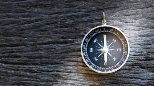 Compass on wooden background, representing the concept of guidance