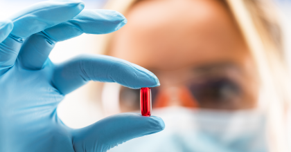 Female scientist holding a red capsule pill