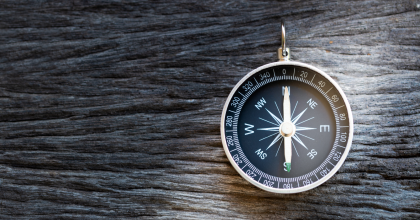 Compass on wooden background, representing the concept of guidance
