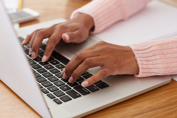 A woman typing on a laptop keyboard