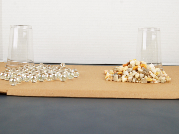 Cup of marbles and cup of rocks dumped on table