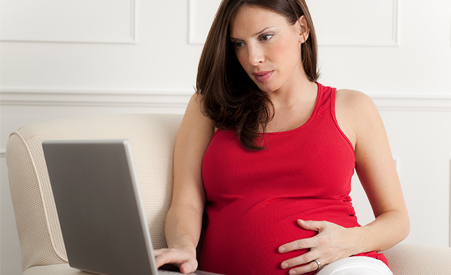 Pregnant woman looking at laptop computer