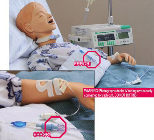 IV tubing erroneously connected to trach cuff on mannequin laying in hospital bed.