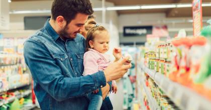 Dad and baby shopping in store aisle.