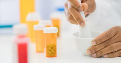 An unrecognizable female pharmacist uses a mortal and pestle to mix a custom medication for a patient