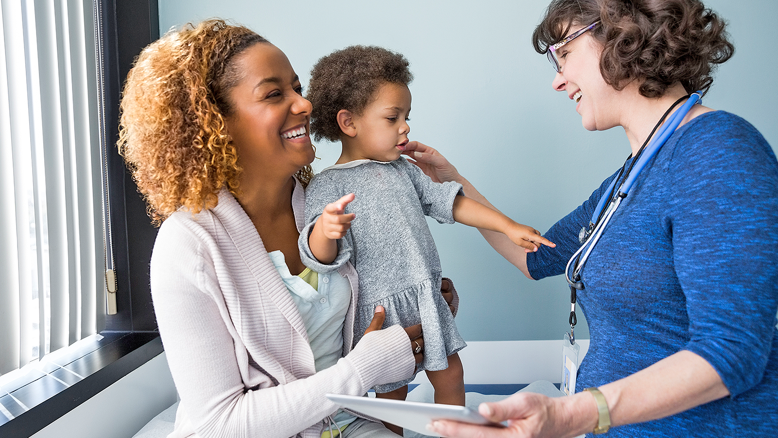 An African-American woman and her young daughter with a female physician.