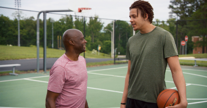 Two men standing on an outdoor basketball court.