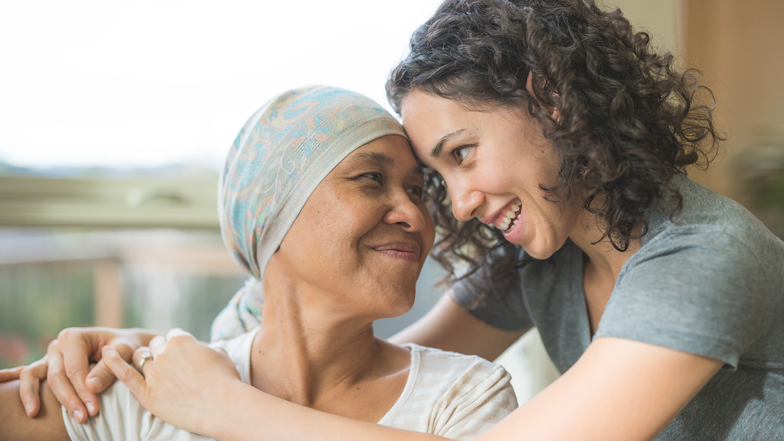 A daughter hugging her sick mother wearing a scarf