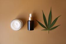 Bank of medicinal cream with CBD oil, bottle of cannabis oil, capsules, on beige background. Flat lay, top view. Design, herbal.