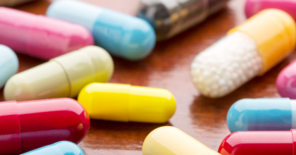 Various colorful medicine capsules on wooden background 