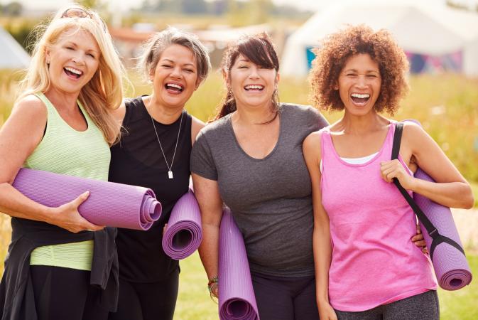 Portrait Of Mature Female Friends On Outdoor Yoga Retreat Walking Along Path Through Campsite