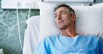 Pensive male patient in hospital bed looking off to the side. 