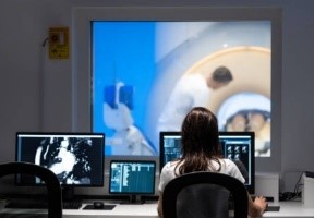 Woman working at desk monitoring multiple screens