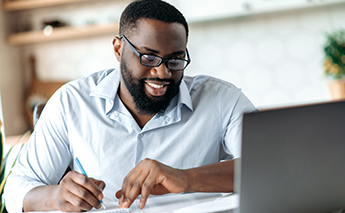 Smiling man looking at laptop screen – Getty Image