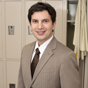 Portrait of FDA medical officer Dr. Ali Mohamadi, standing in a gym locker room