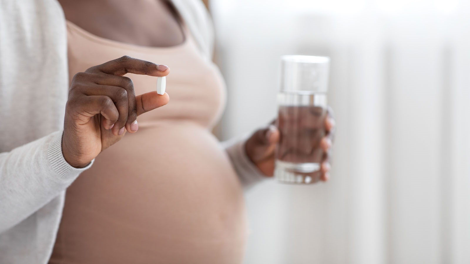 Pregnant Woman holding a pill and a glass of water