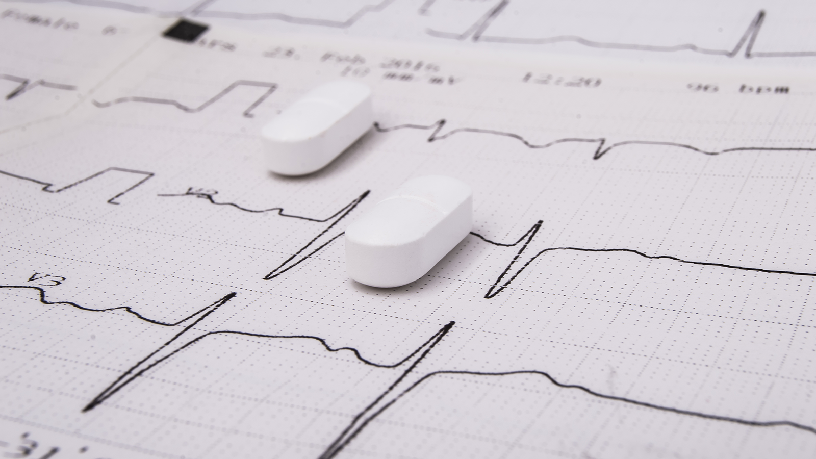 White pills on paper with EKG trace