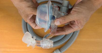 Hands holding CPAP mask assembly. Cleaning CPAP Machines and Accessories.
