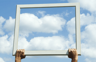 Representation of transparency with a photo of two hands holding a transparent window frame in a blue sky with white clouds.